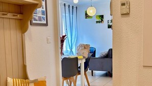 Ein modernes Wohnzimmer mit einer Couch, einem Esstisch mit Stühlen und einem durch einen offenen Durchgang einsehbaren Küchenbereich.