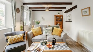 Uma sala de estar com sofá, poltrona, mesa de centro e estante de livros.