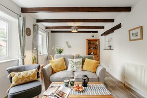 A living room with a sofa, armchair, coffee table, and a bookshelf. - 1 Bed in Parracombe (oc-l28026) (Trentishoe)