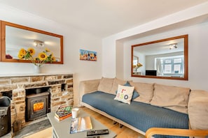 A living room with a stone fireplace, a sofa, a coffee table with books and a remote, and a large mirror. - 3 Bed in Little Haven (oc-h27960) (Little Haven)