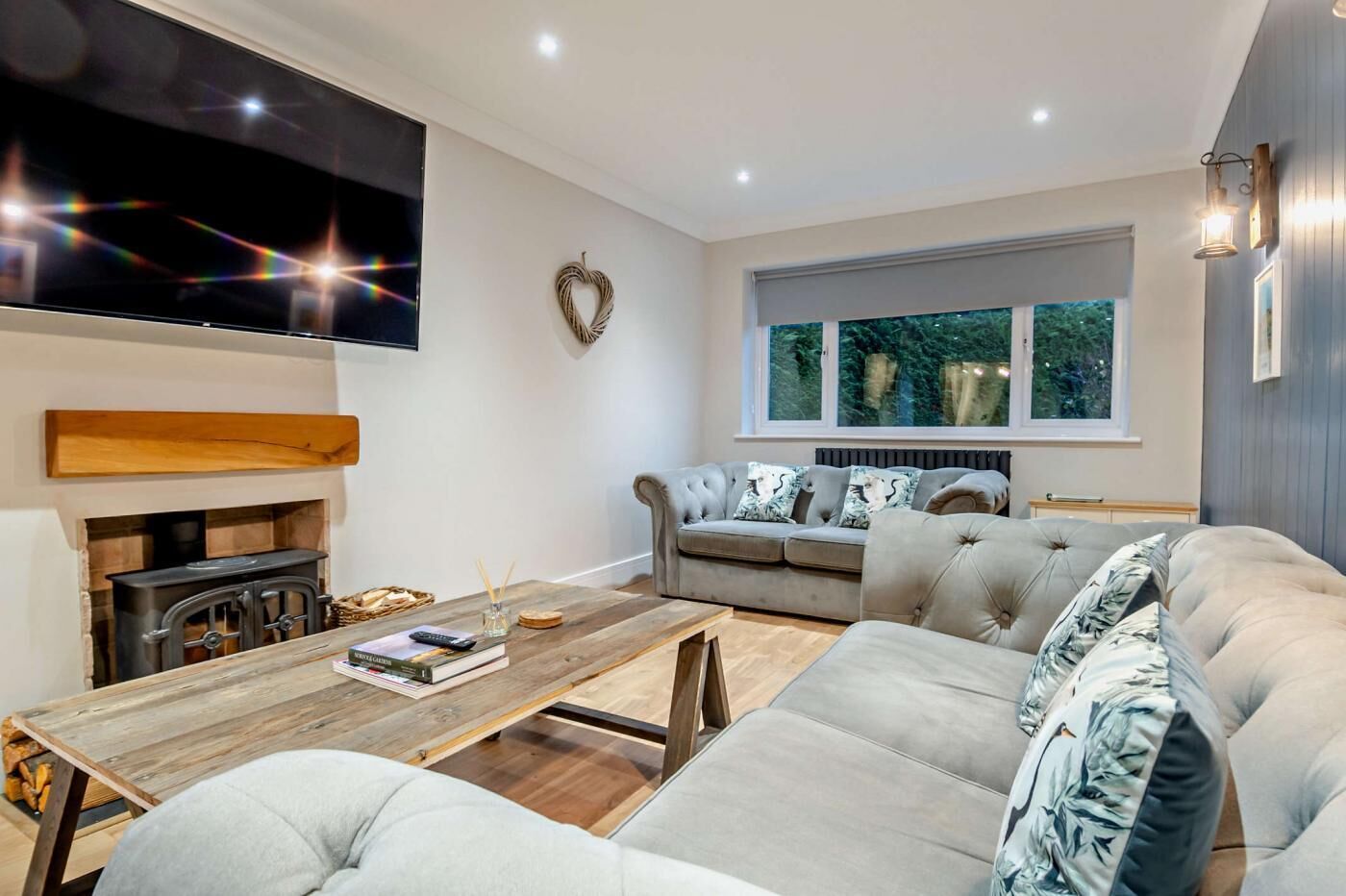 Un salon moderne avec une cheminée, un canapé, une table basse et un téléviseur fixé au mur.