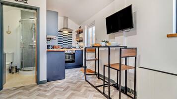 A modern kitchen with a herringbone floor, a built-in oven, and a TV mounted on the wall.