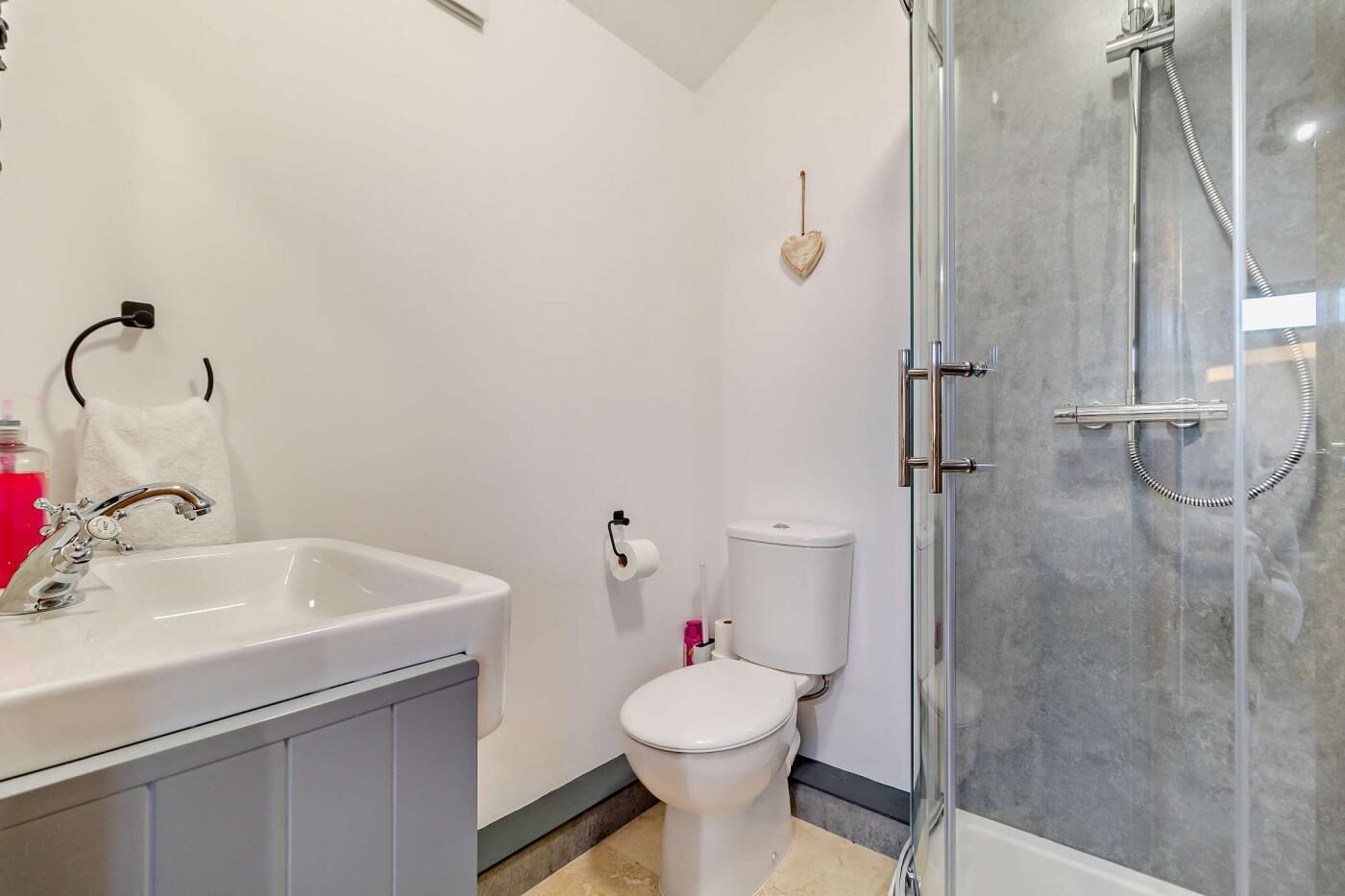 A modern bathroom with a white sink, toilet, and glass-enclosed shower.