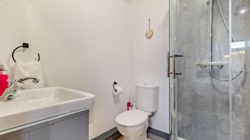 A modern bathroom with a white sink, toilet, and glass-enclosed shower.