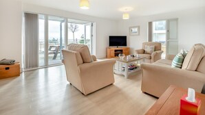 A modern living room with a sofa, armchairs, a coffee table, and a TV. - 2 Bed in Bournemouth (oc-b27914) (Bournemouth)