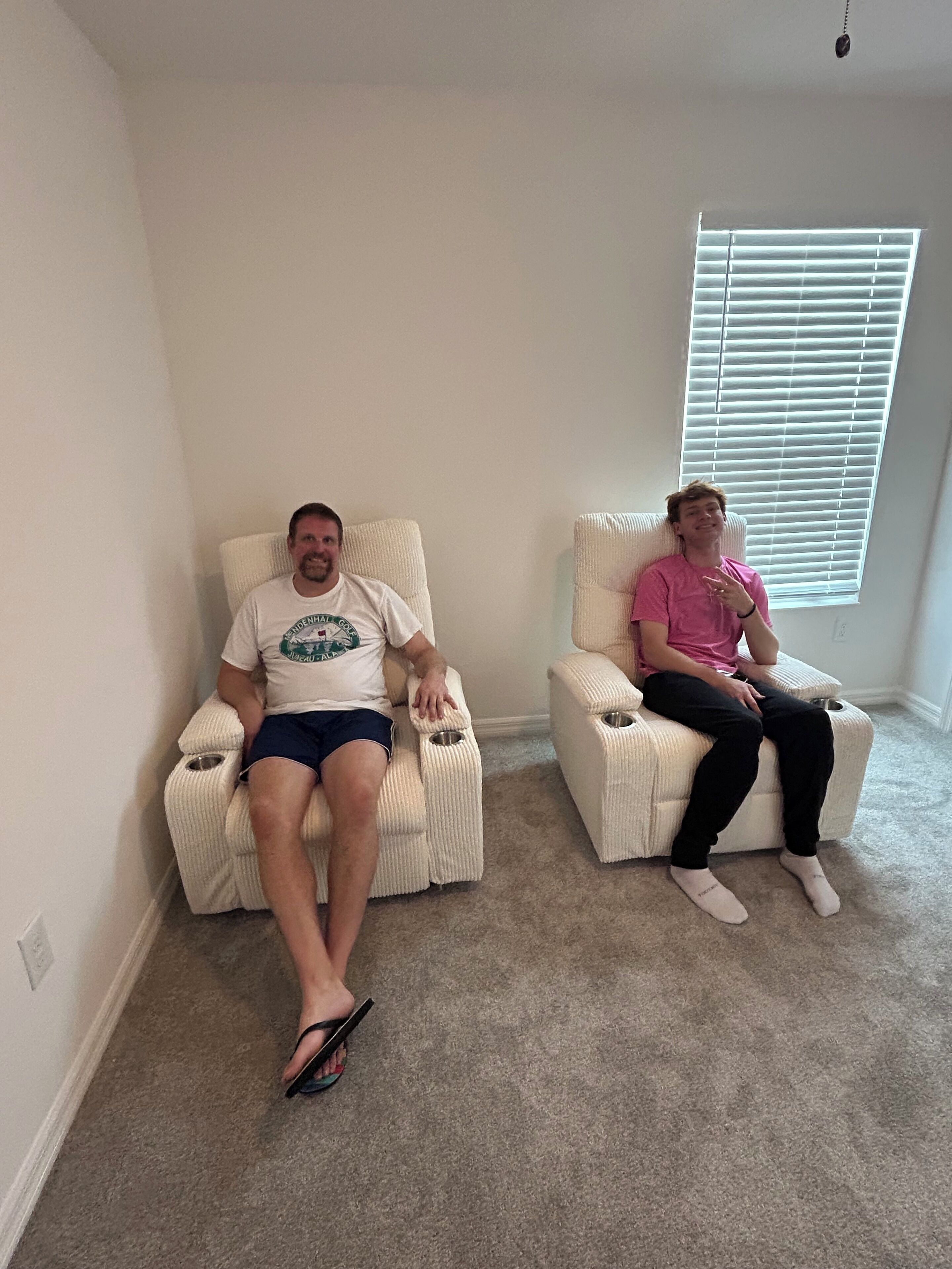 Deux fauteuils inclinables dans une pièce dont le sol est recouvert d’une moquette et qui possède une fenêtre avec des stores.