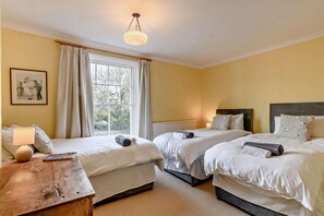 Une chambre d’hôtel avec deux lits simples, une table de chevet en bois, une lampe de table et une fenêtre avec des rideaux.