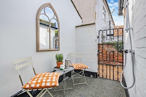 A small outdoor seating area with two chairs and a table, a potted plant, and a coffee pot. - 1 Bed in Southwold (oc-b27959) (Southwold)