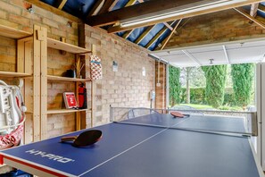 Ein Tischtennis-Tisch mit Netz, eine Brandschutzdecke und ein Feuerlöscher an einer Ziegelwand.