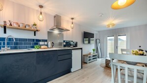 A modern kitchen with a central island, built-in appliances, and pendant lighting. - 1 Bed in Newquay (oc-l28083) (Newquay)
