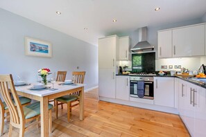 A modern kitchen with white cabinets, a stainless steel range hood, and an oven.