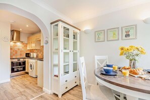 A modern kitchen with a dining area, featuring a built-in oven, microwave, and washing machine.