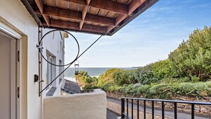 A balcony with a view of the sea, a stone wall, and a wooden ceiling. - 2 Bed in Putsborough (oc-a22903) (Croyde)