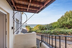 A balcony with a view of the sea, a stone wall, and a wooden ceiling. - 2 Bed in Putsborough (oc-a22903) (Croyde)