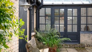 A conservatory with a dark blue door, a brick wall, and a stone bench. - 3 Bed in Yoxford (oc-t28018) (Aldeburgh)