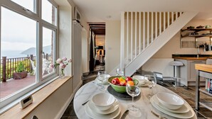 A dining area with a view of the sea, a staircase, and a kitchen. - 3 Bed in Lynton (oc-n28090) (Lynmouth)