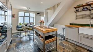 A modern kitchen with a dining area, a staircase, and a view of the outside. - 3 Bed in Lynton (oc-n28090) (Lynmouth)
