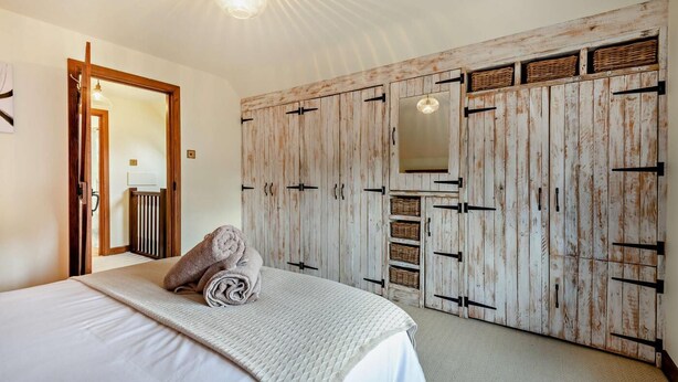 Ein Schlafzimmer mit einem Bett, einem Holzschrank mit Körben und einem Spiegel.