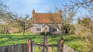 Une maison traditionnelle avec un toit en tuiles, une porte d’entrée et un chemin qui y mène.