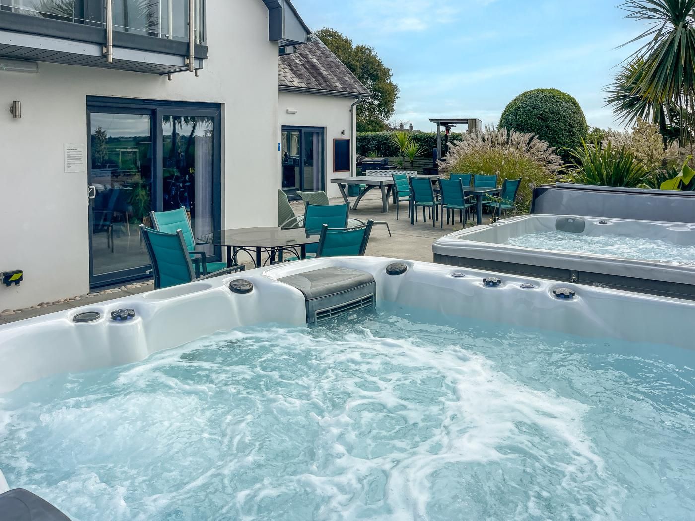 Ein Wellnessbereich mit zwei Whirlpools und Sitzgelegenheiten im Freien.