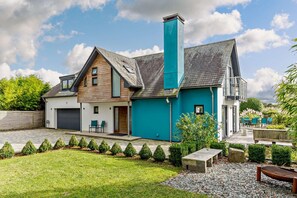 A modern two-story house with a garage, a covered patio, and a well-maintained garden.