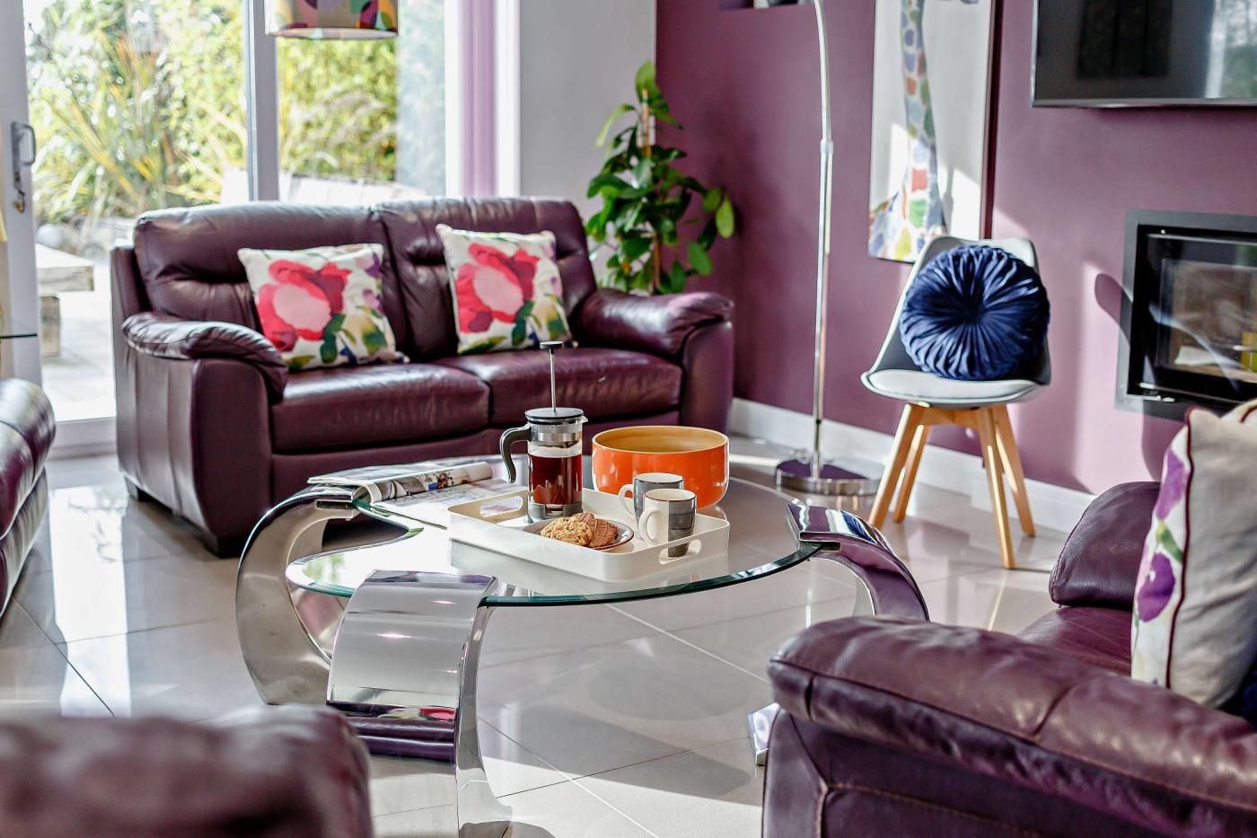 A modern living room with a leather sofa, a glass coffee table, and a television.