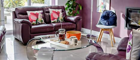 A modern living room with a leather sofa, a glass coffee table, and a television.