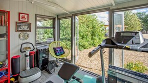 Et hjemmegym med træningsudstyr, et løbebånd og en ventilator.