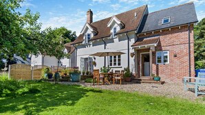 Une maison à deux étages avec un patio, une clôture en bois et des plantes en pot.