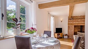 Un coin repas avec une table dressée pour deux personnes, une cheminée et un téléviseur en arrière-plan.