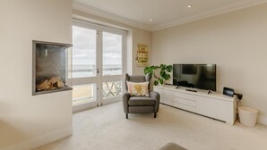 Una sala de estar moderna con un televisor grande, un sillón gris y una chimenea.
