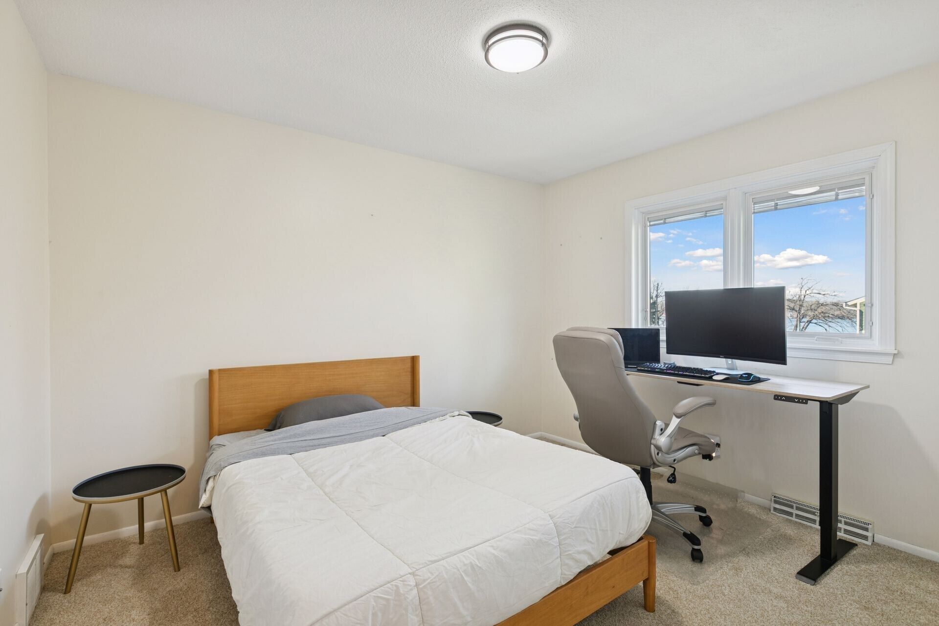 Un dormitorio con una cama, un escritorio con una computadora, una silla y una ventana.