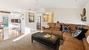 Ein modernes Wohnzimmer mit Ledersofa, Couchtisch und einer Küche im Hintergrund.