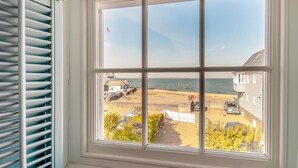 A window with a view of a beach, a parked car, and a building. - 3 Bed in Whitstable (oc-o28123) (Whitstable)
