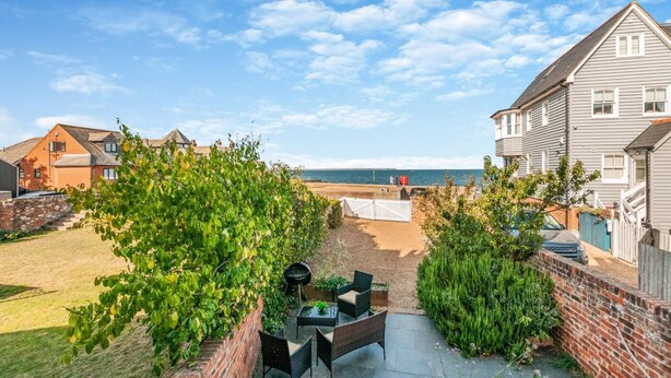 A residential backyard with a patio, a view of the sea, and a white fence. - 3 Bed in Whitstable (oc-o28123) (Whitstable)