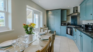 A modern kitchen with teal cabinets, a dining table set for four, and a window providing natural light.