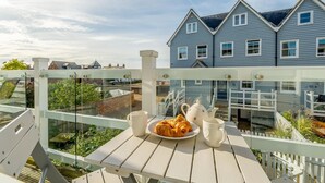Un balcon avec une table préparée pour le petit-déjeuner, comprenant des croissants, une théière et une tasse.