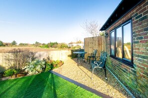 A patio with a table and chairs, a brick wall, and a view of the countryside.