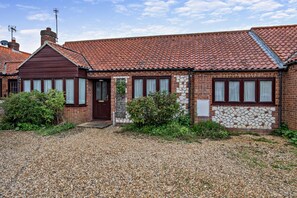 A two-story brick house with a red-tiled roof, a front door, and a small front garden.