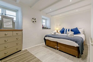 Une chambre à coucher comprenant un lit, une commode, un miroir, une fenêtre et un élément décoratif mural.