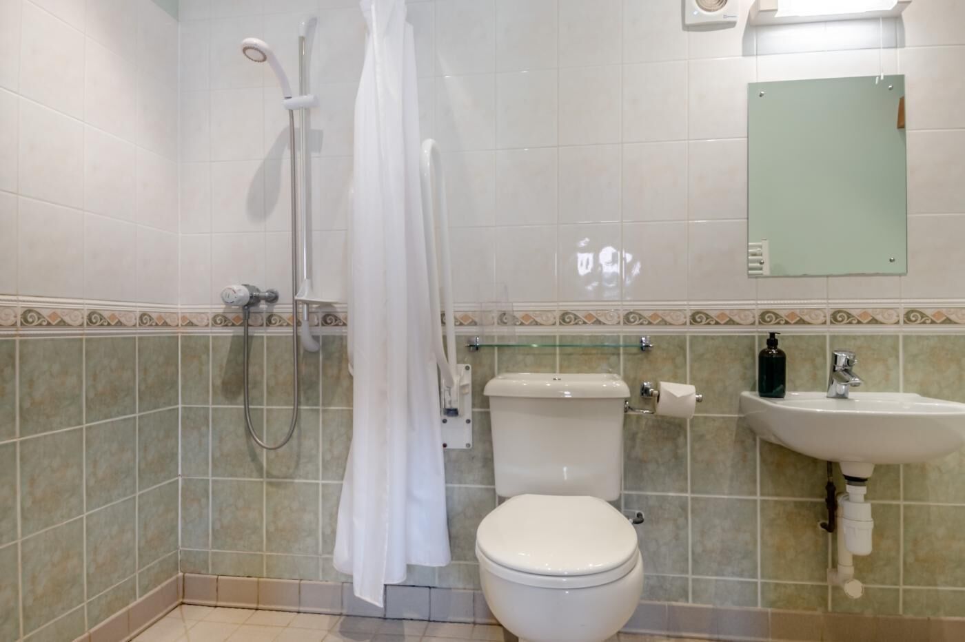 A bathroom with a toilet, shower, and sink.