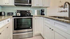 Eine moderne Küche mit weißen Schränken, einem Edelstahlbackofen, einer Mikrowelle und einer Arbeitsplatte aus Granit.