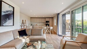 Una sala de estar moderna con un sofá, una mesa de centro con juego de té y una zona de comedor con una mesa y sillas.