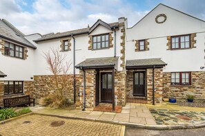 A two-story house with stone accents, a front porch, and a small garden area. - 3 Bed in Padstow (oc-c28137) (Padstow)