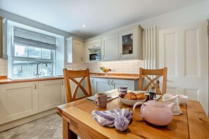 Una cocina moderna con armarios blancos, una mesa de comedor de madera y una ventana con persianas.