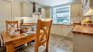 A modern kitchen with white cabinetry, a central island, and a window providing natural light. - 3 Bed in St. Breward (oc-g28144) (Saint Breward)