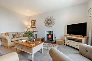 A living room with a sofa, coffee table, TV stand, fireplace, and decorative wall piece. - 3 Bed in St. Breward (oc-g28144) (Saint Breward)