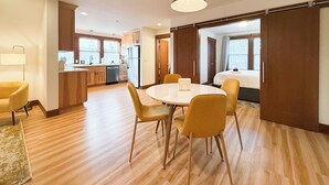 Moderni hotellihuone, jossa on ruokailutila, pieni keittiö ja suuri sänky.