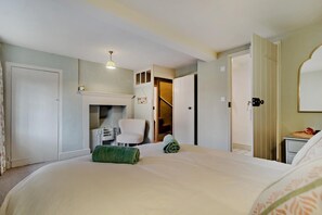 A bedroom with a bed, a chair, a fireplace, and a staircase leading to another room. - 3 Bed in Southwold (oc-r11173) (Southwold)