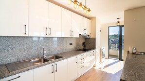 A modern kitchen with granite countertops, stainless steel appliances, and white cabinetry. - GuestReady - Seaview Escape (Câmara de Lobos)